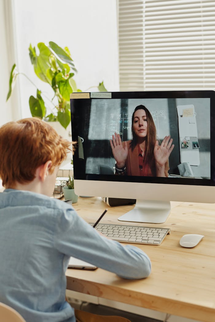 features-03 A child participates in online learning through a video call with a teacher, using a desktop setup indoors.