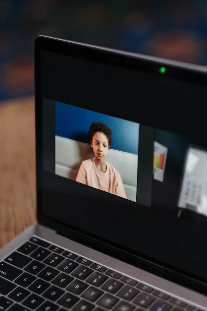 A young African American girl participates in an online class at home on a laptop.